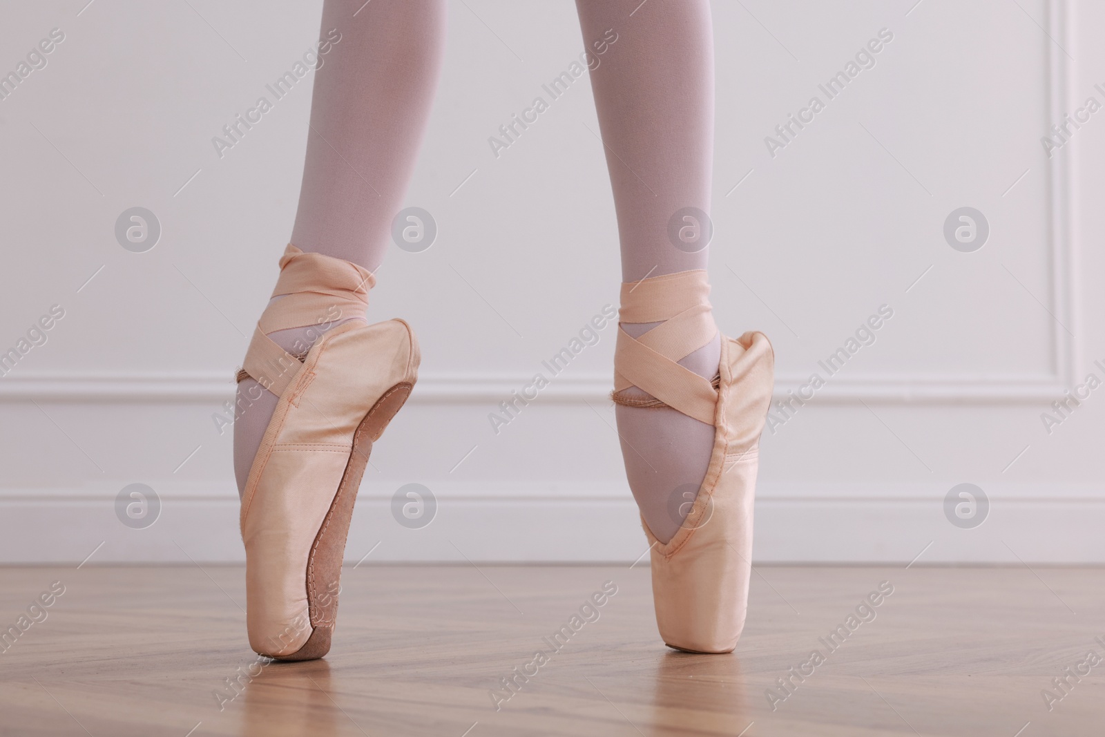 Photo of Little ballerina practicing dance moves in studio, closeup of legs