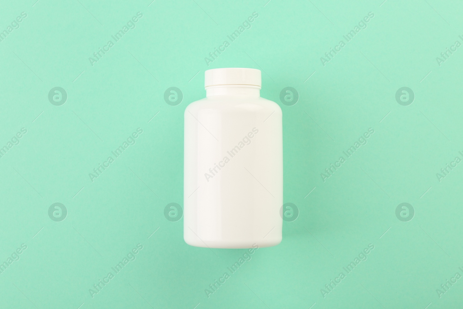 Photo of Blank white pill bottle on turquoise background, top view. Space for text