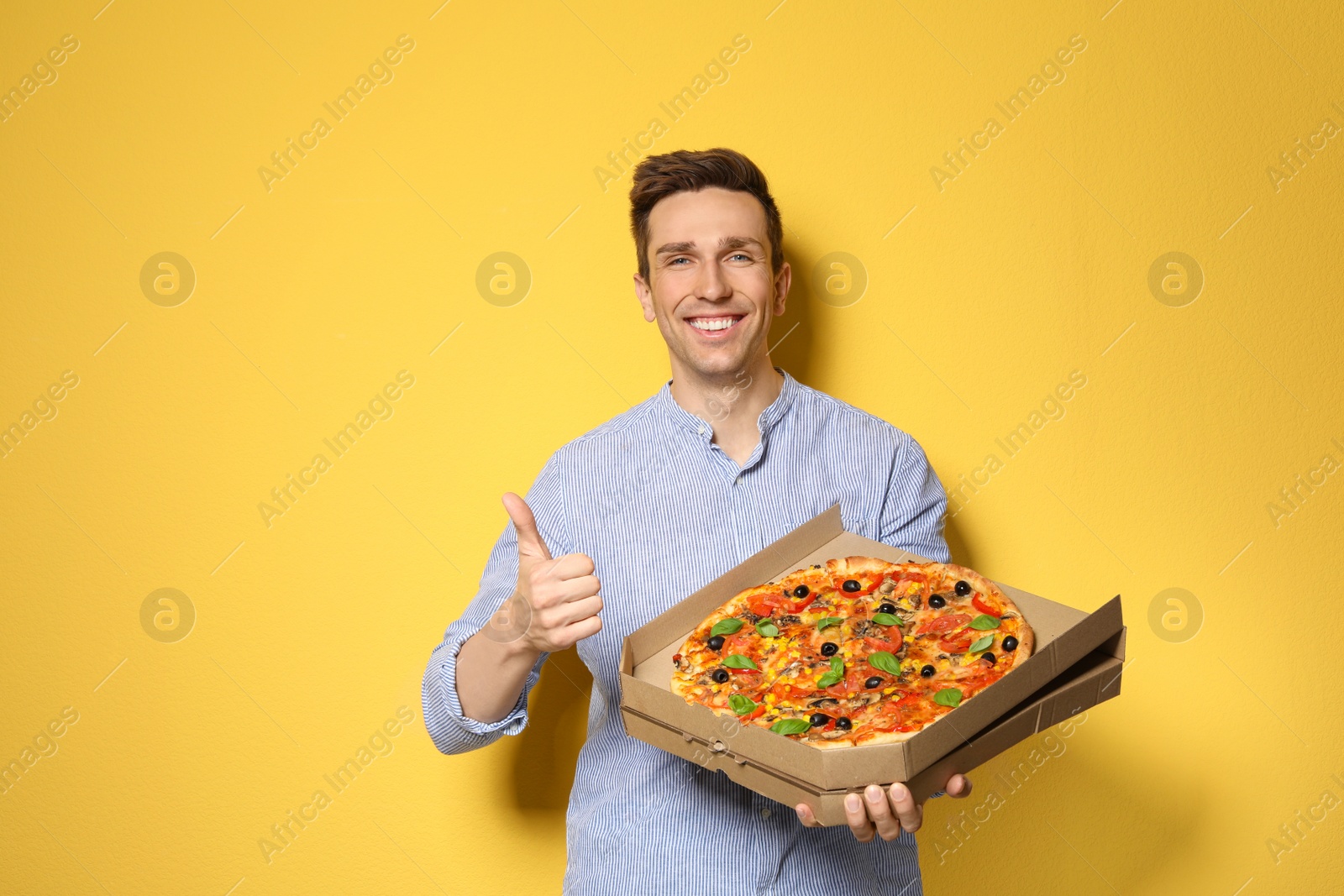 Photo of Attractive young man with delicious pizza on color background