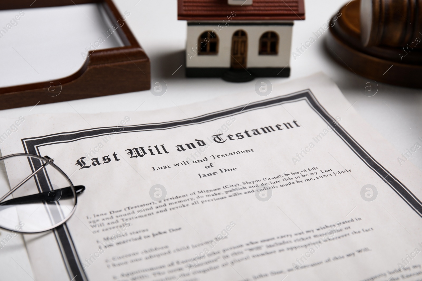 Photo of Last will and testament near house model, glasses on white table, closeup