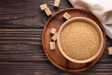 Photo of Brown sugar in bowl on wooden table, top view. Space for text