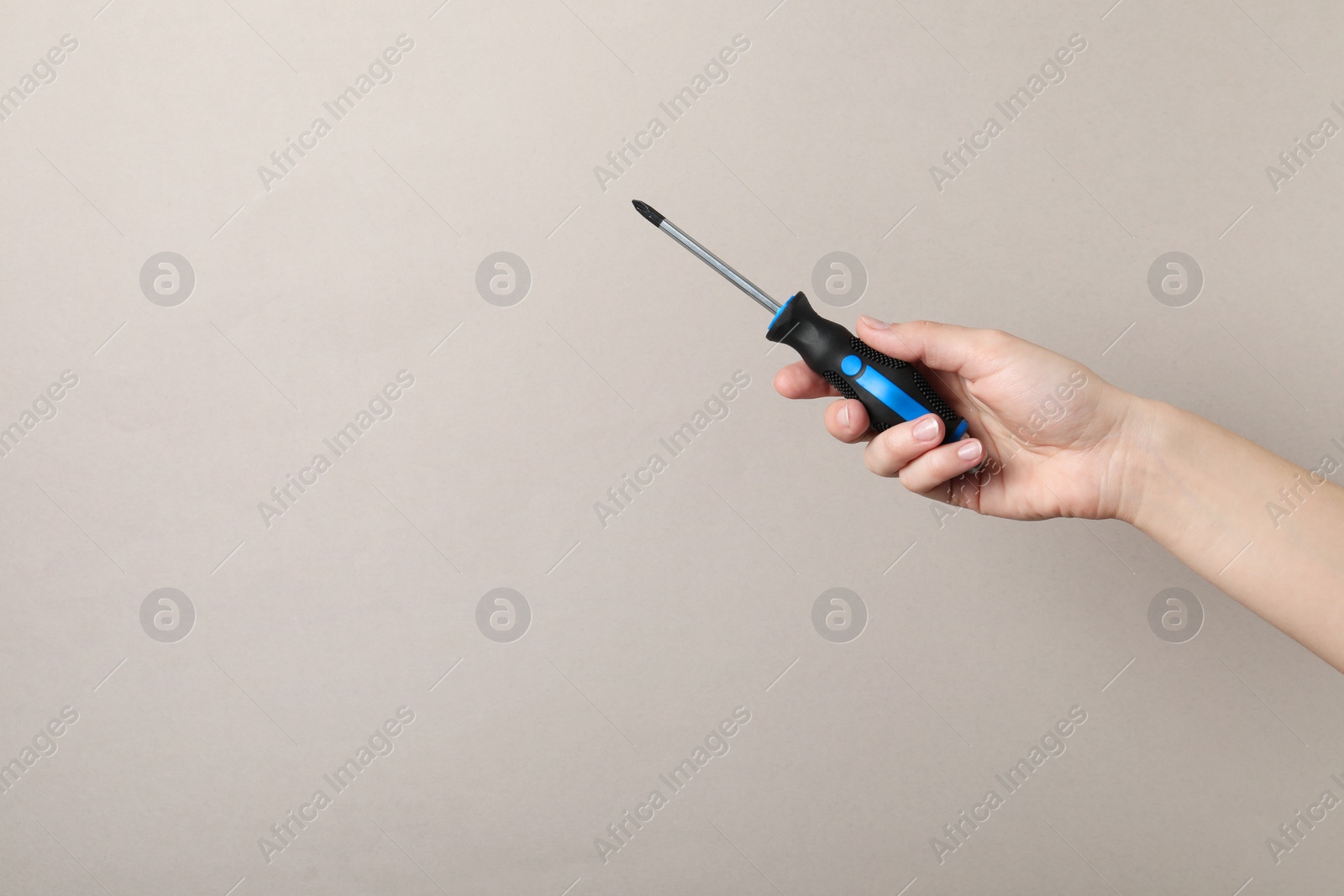 Photo of Woman holding screwdriver on grey background, closeup. Space for text