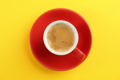 Cup of tasty coffee on yellow background, top view