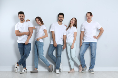 Group of young people in stylish jeans near light wall