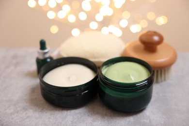 Photo of Natural scrub and other body care products on grey table against blurred lights