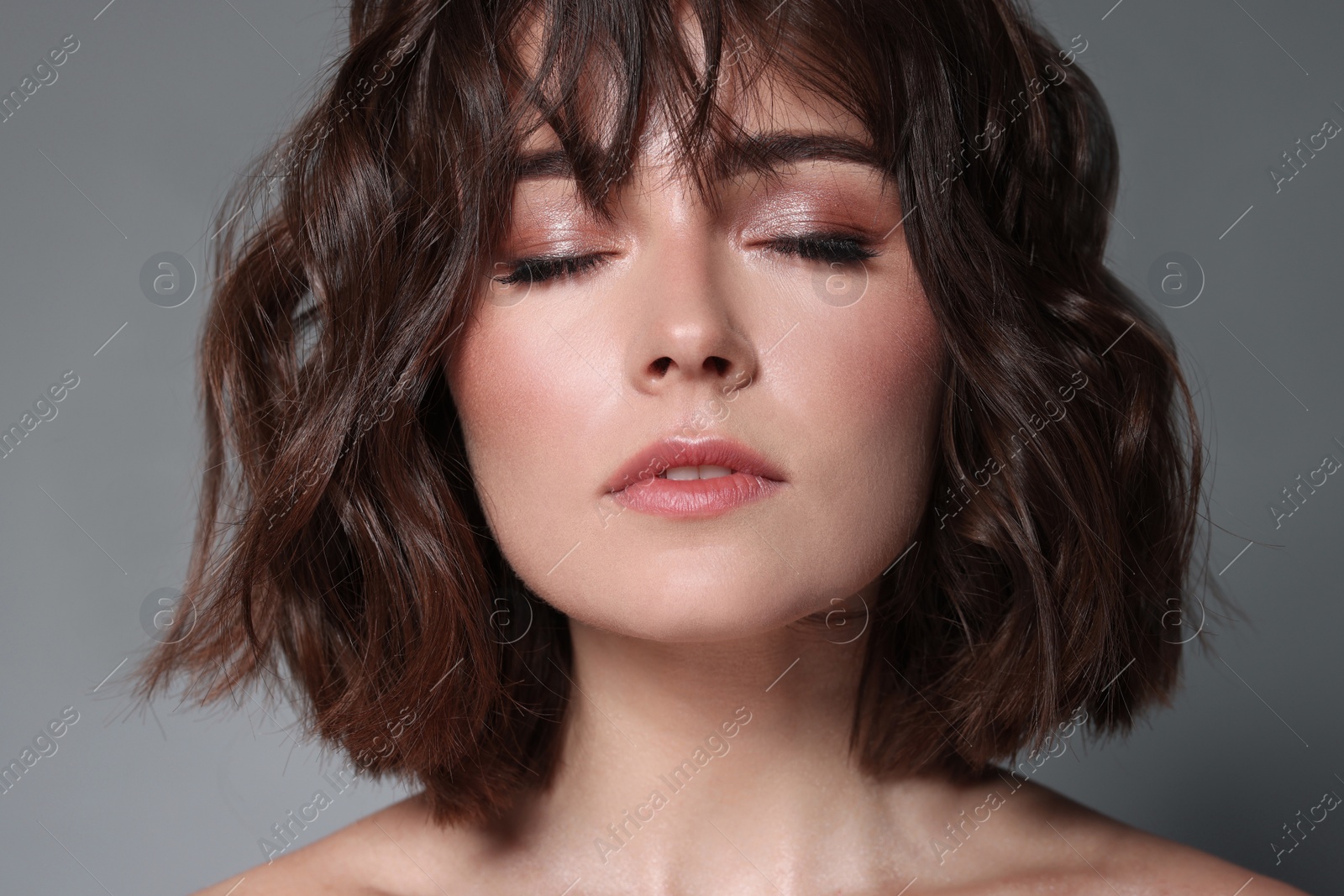 Photo of Beautiful young woman with wavy hairstyle on grey background