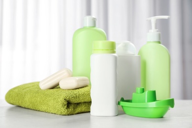 Photo of Baby cosmetic products, toy and towel on table indoors