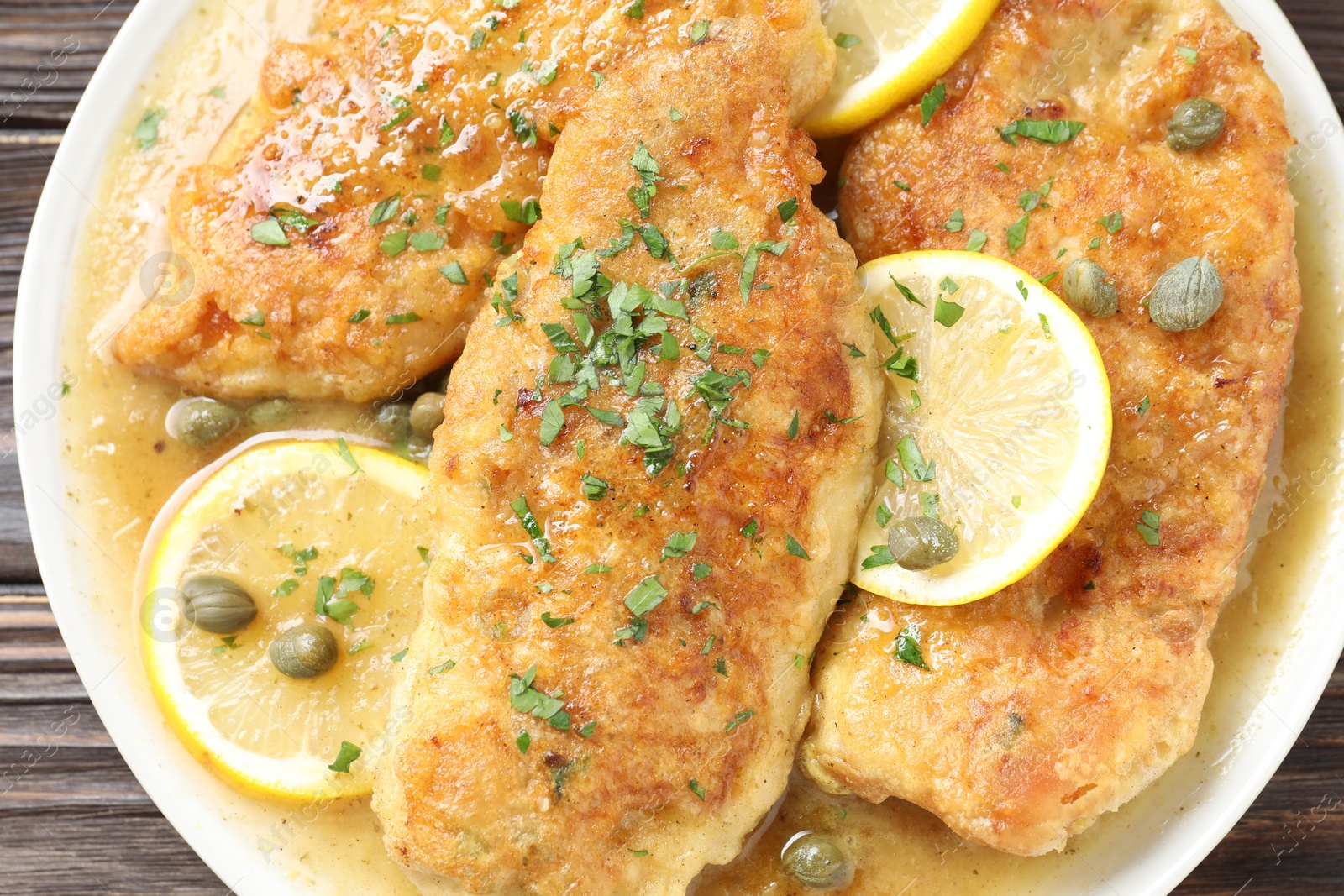 Photo of Delicious chicken piccata on wooden table, top view