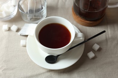 Photo of Tasty tea in cup and sugar cubes on light table