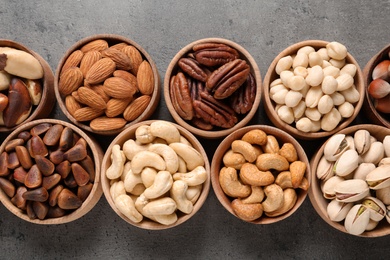 Photo of Flat lay composition with organic nuts on grey background, top view. Snack mix