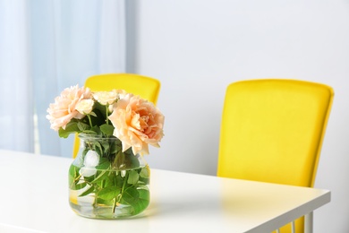 Vase with blooming flowers on table indoors