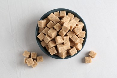 Photo of Brown sugar cubes on light textured table, flat lay