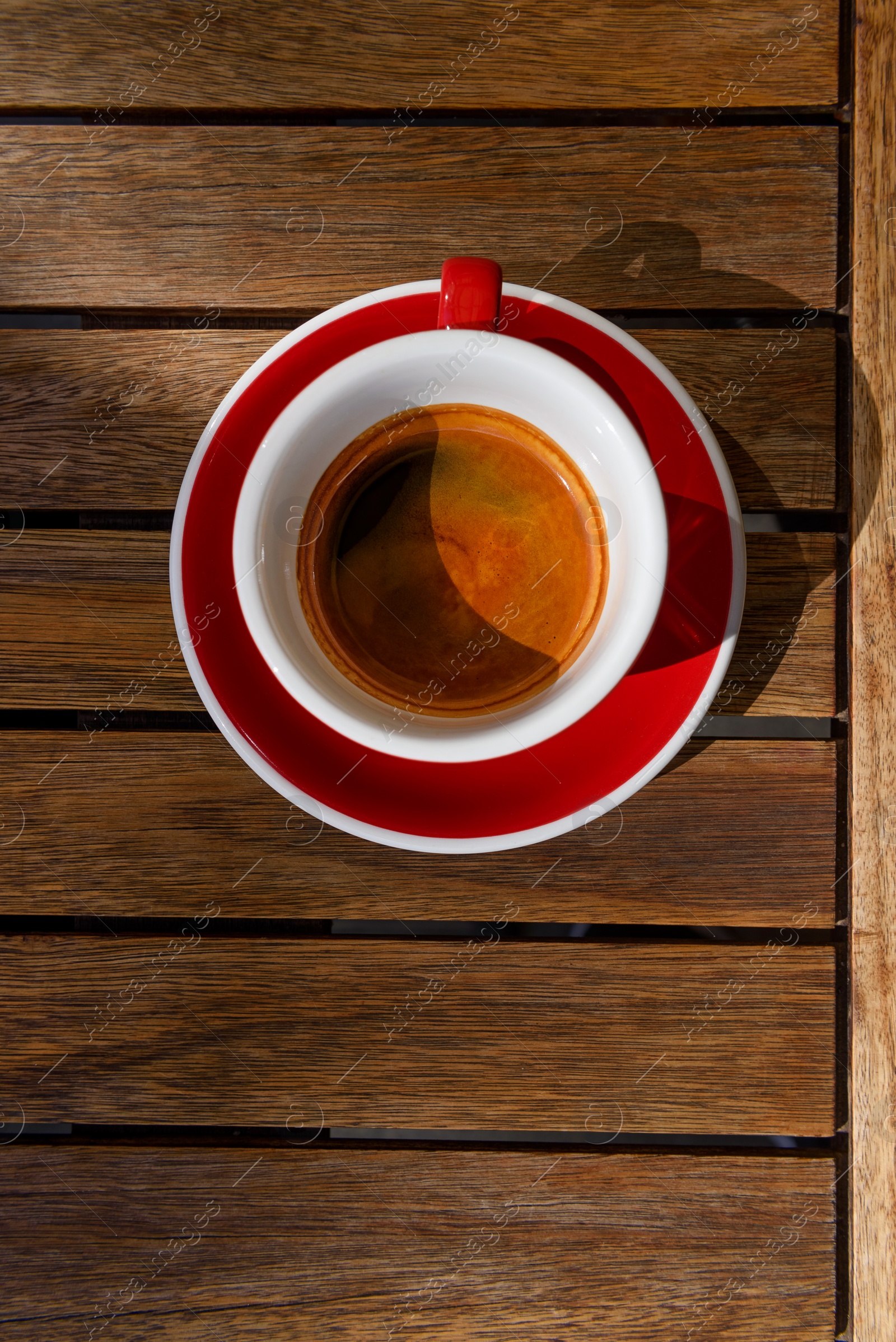 Photo of Cup of aromatic hot coffee on wooden table, top view