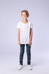 Photo of Cute little boy in casual outfit on light background