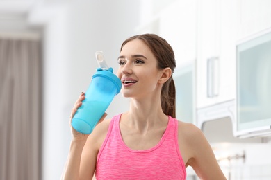 Photo of Athletic young woman drinking protein shake in kitchen