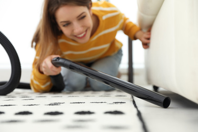 Photo of Young woman using vacuum cleaner at home