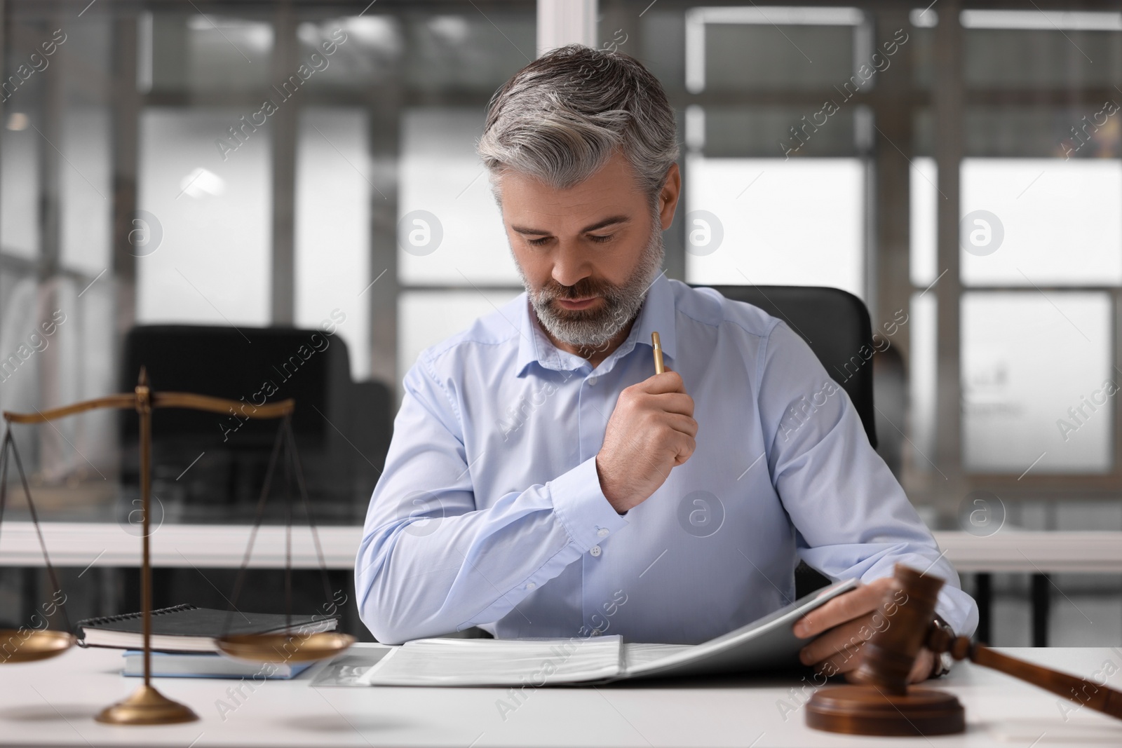 Photo of Serious lawyer working at table in office