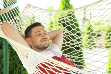 Photo of Man sleeping in hammock outdoors on warm summer day