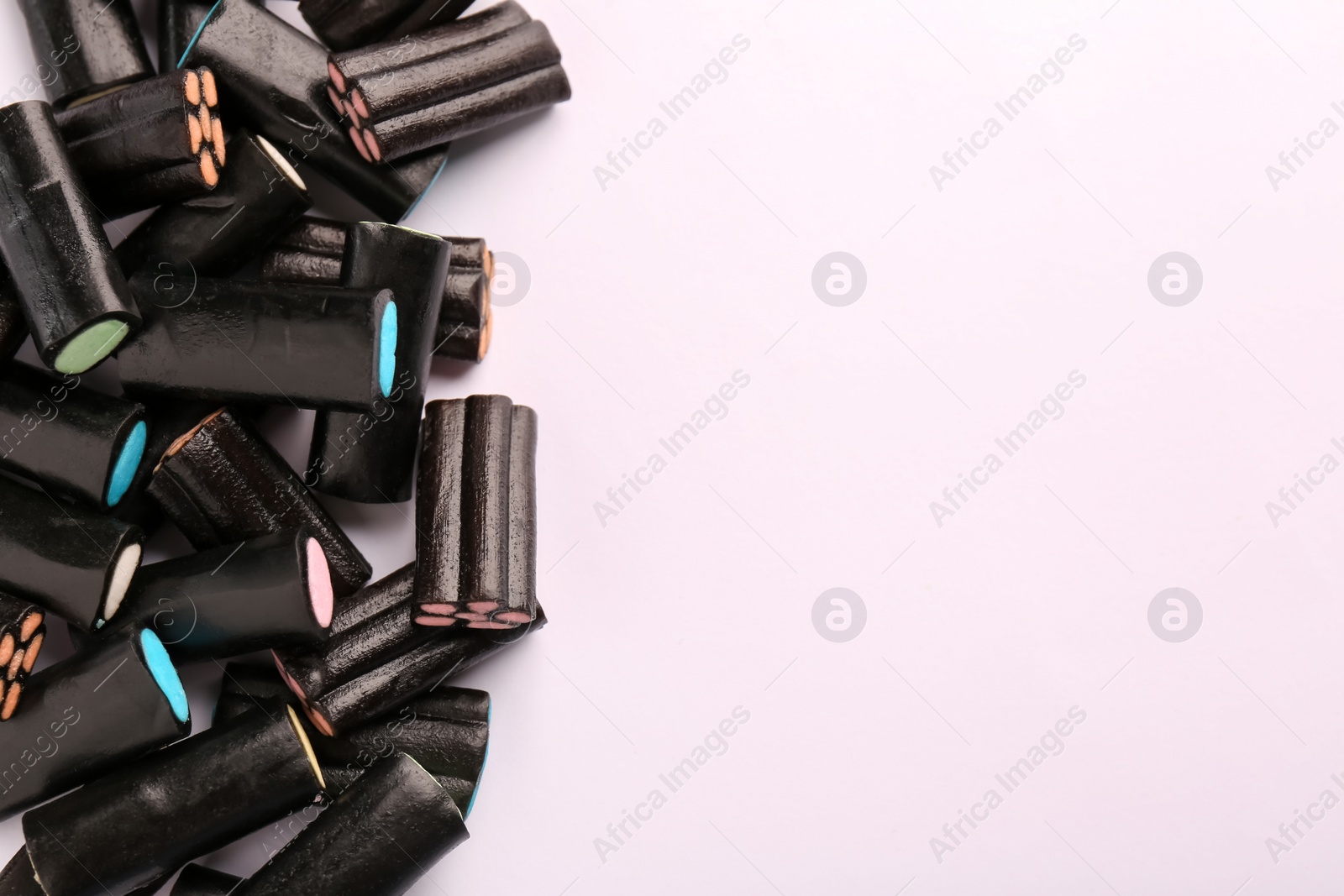 Photo of Tasty liquorice candies on light background, top view. Space for text