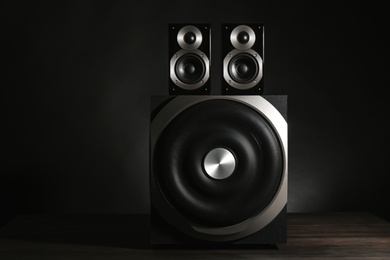 Photo of Modern powerful audio speaker system on table against black background