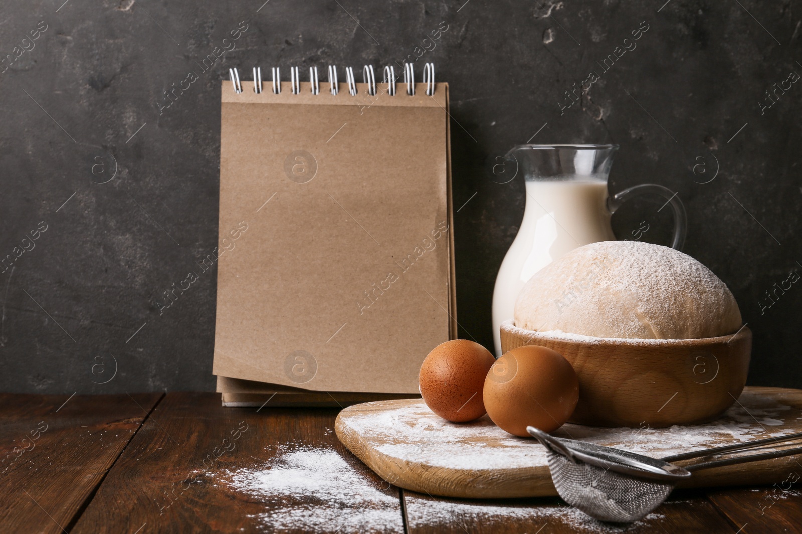 Photo of Composition with raw eggs and blank notebook on wooden table. Baking pie