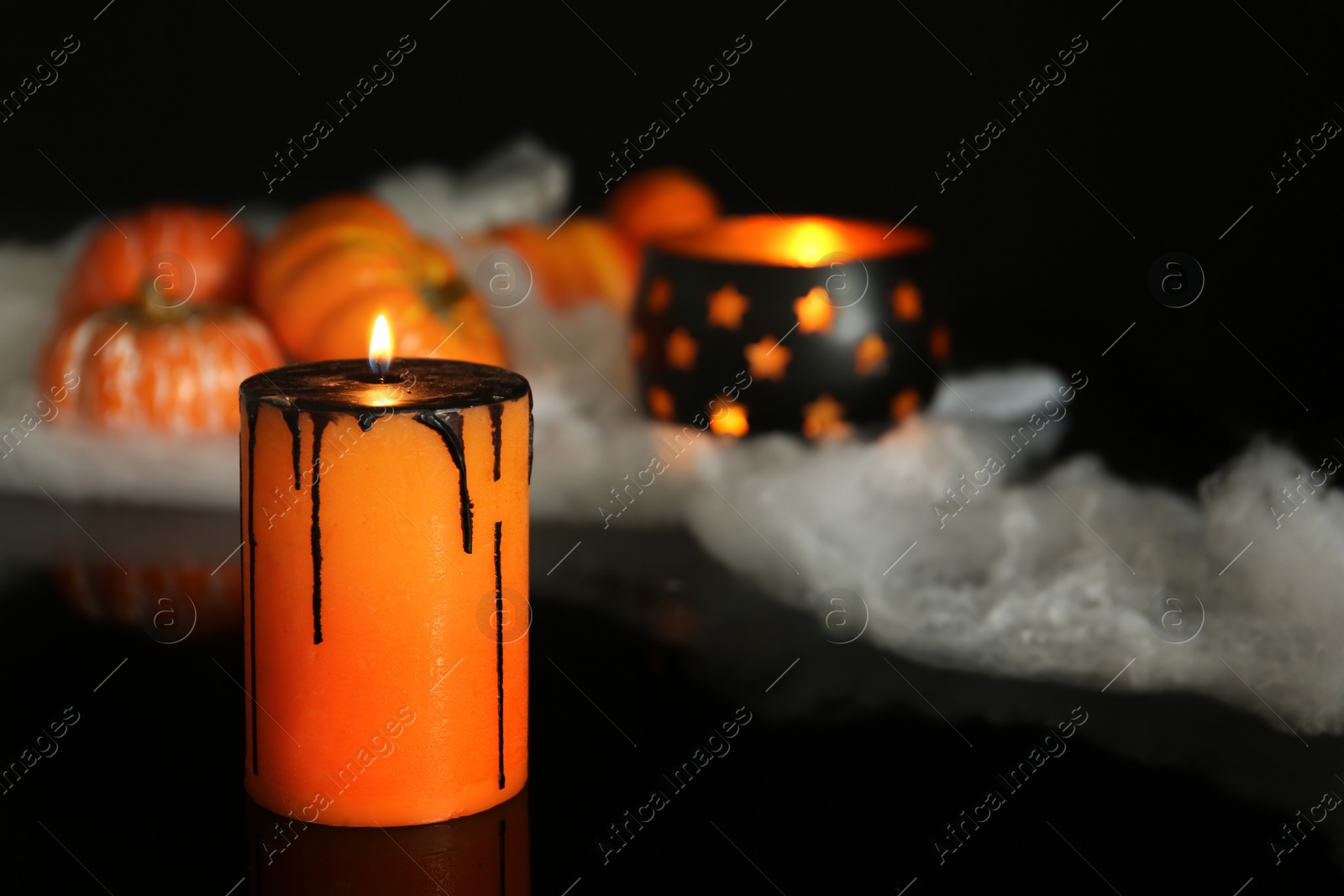 Photo of Burning candle and decor on black background. Halloween celebration