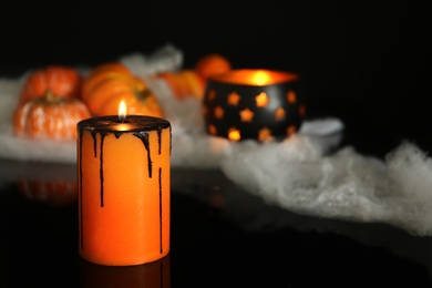 Photo of Burning candle and decor on black background. Halloween celebration