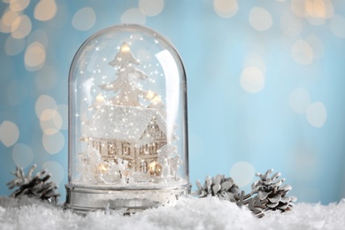 Photo of Beautiful snow globe and cones against blurred Christmas lights. Space for text