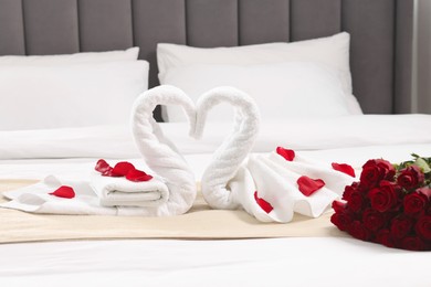 Photo of Honeymoon. Swans made of towels and beautiful red roses on bed