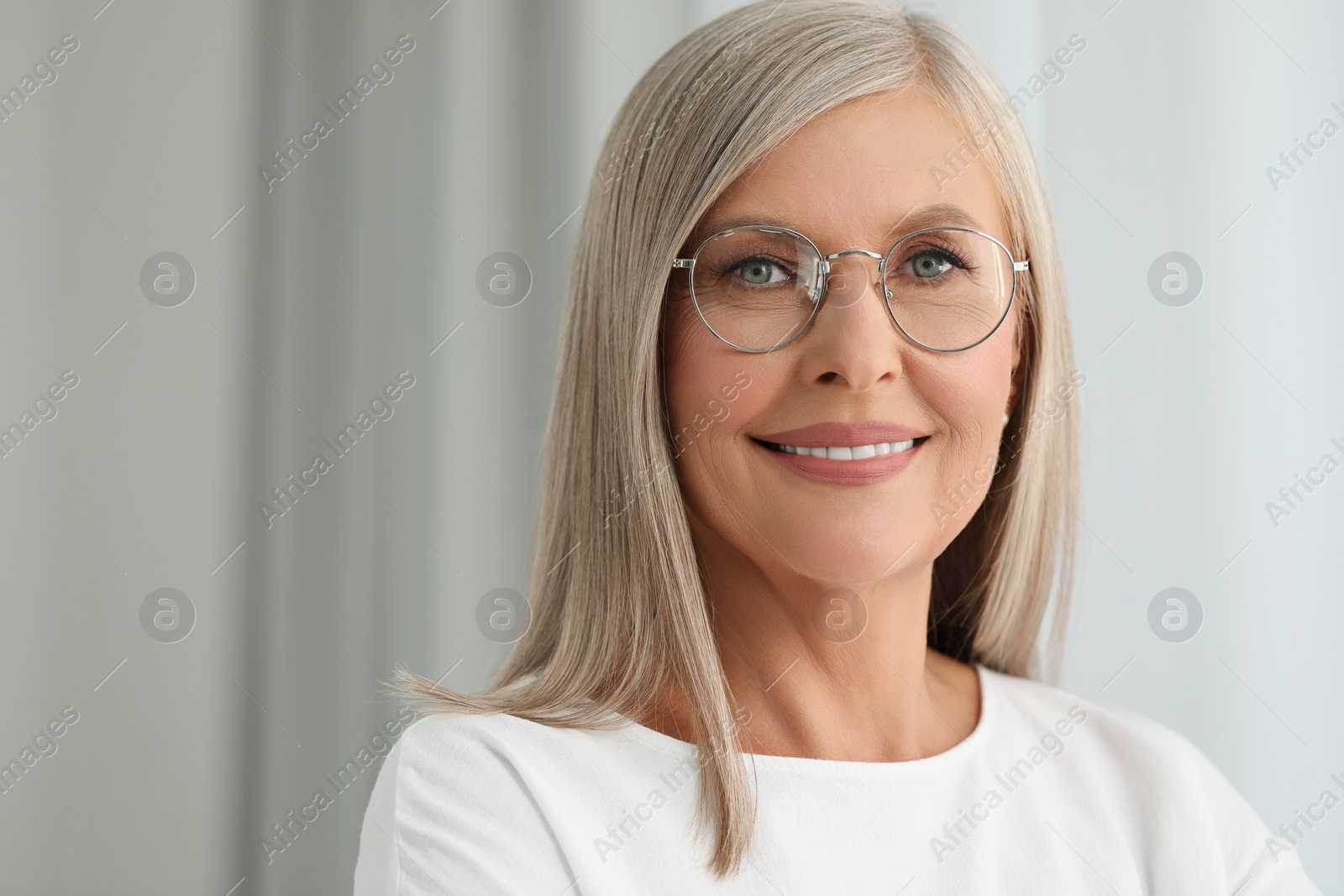 Photo of Portrait of beautiful middle aged woman in eyeglasses on blurred background. Space for text
