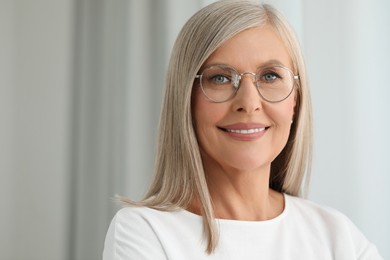 Portrait of beautiful middle aged woman in eyeglasses on blurred background. Space for text