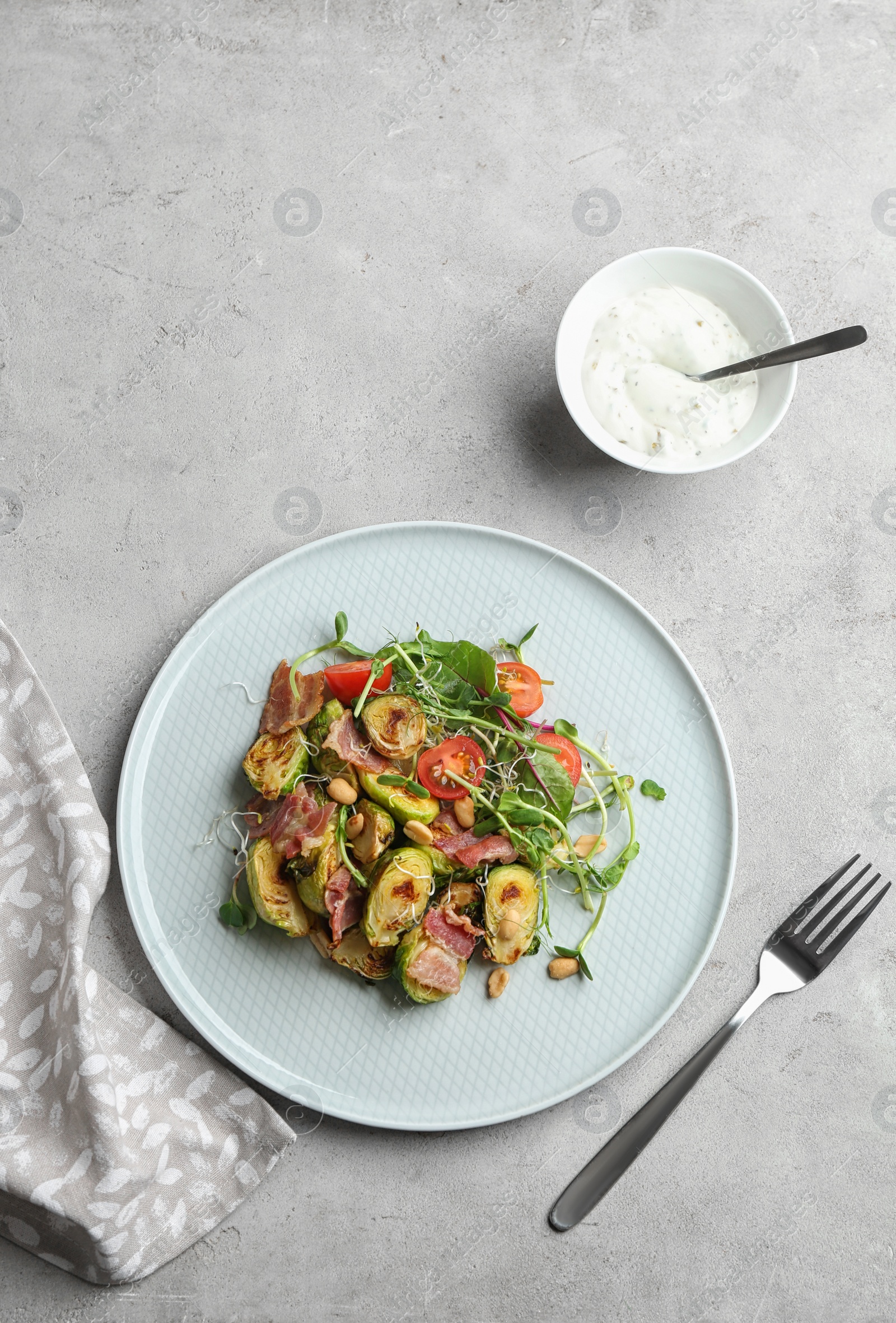 Photo of Delicious roasted Brussels sprouts with bacon served on light grey table, flat lay