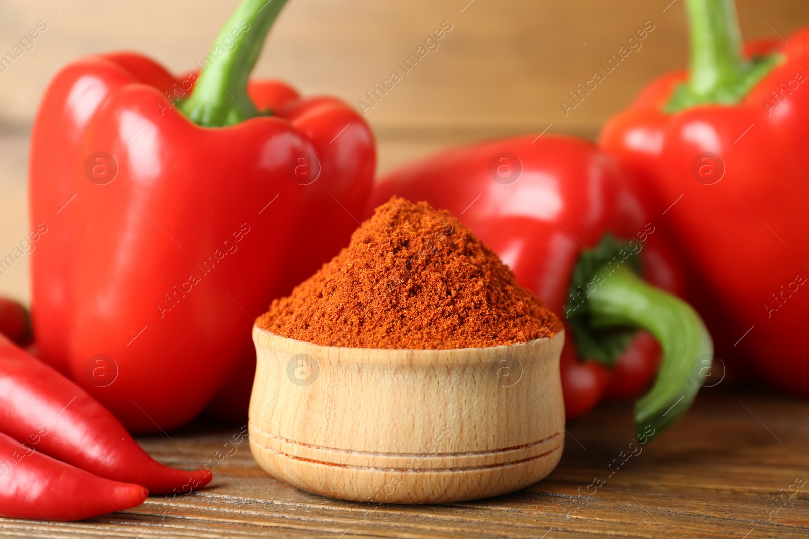 Photo of Paprika powder and fresh chili peppers on wooden table, closeup