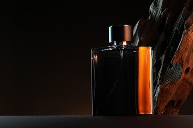 Luxury men`s perfume in bottle on grey table against dark background, space for text