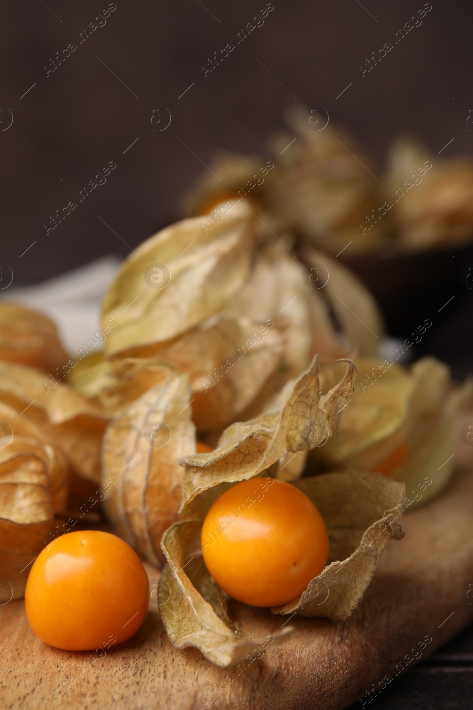 Photo of Ripe physalis fruits with calyxes on wooden table, closeup