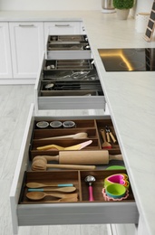 Photo of Open drawers with different utensils in kitchen