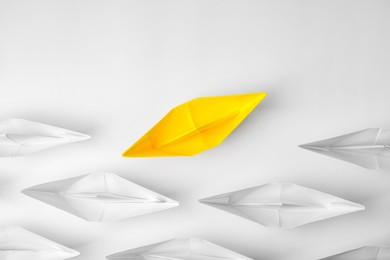 Yellow paper boat among others on white background, flat lay. Uniqueness concept