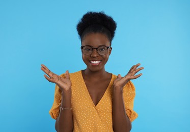 Photo of Portrait of beautiful young woman in eyeglasses on light blue background