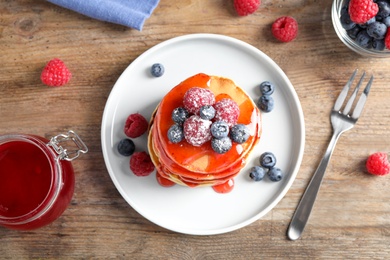 Tasty pancakes with berries served on wooden table, flat lay