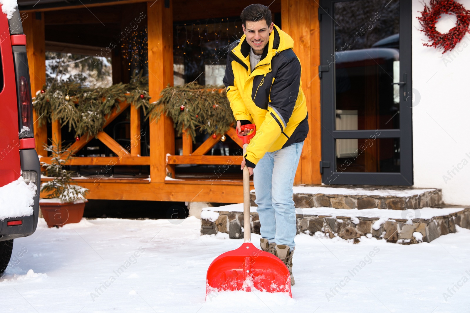 Photo of Man removing snow from house yard with shovel on winter day