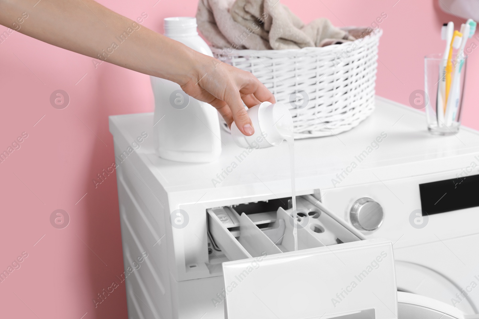 Photo of Woman pouring detergent into drawer of washing machine in laundry room, closeup