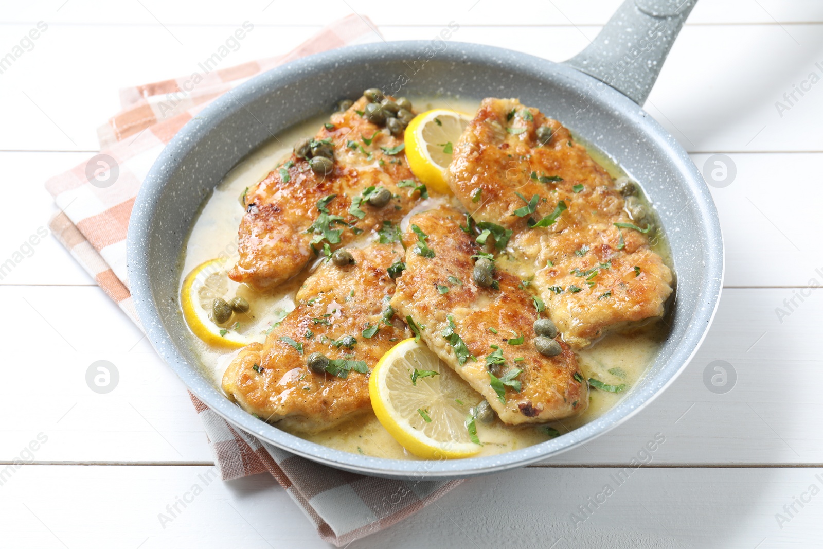 Photo of Delicious chicken piccata on white wooden table, closeup