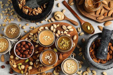 Photo of Making nut butters from different nuts. Flat lay composition on light grey table