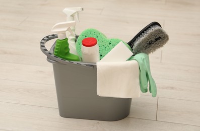 Photo of Different cleaning products in bucket on floor indoors