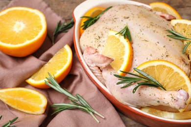 Photo of Chicken with orange slices and rosemary on table