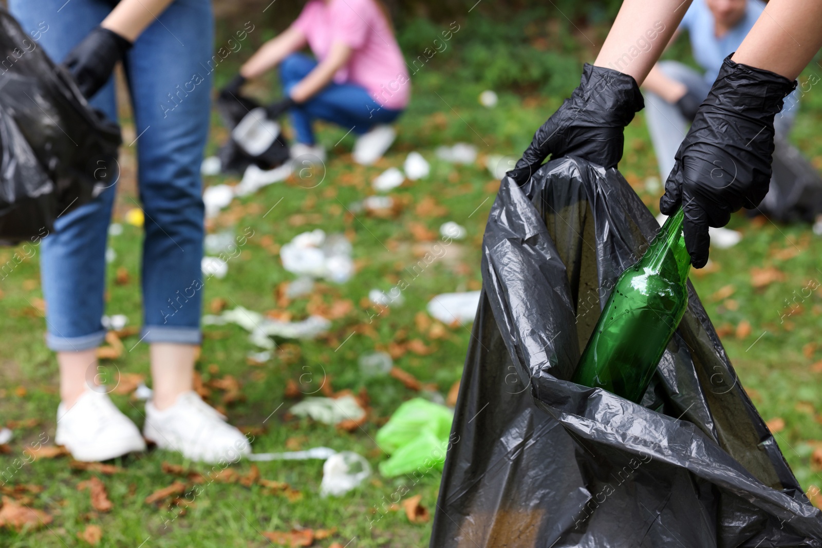 Photo of Woman with plastic bag collecting garbage in park, closeup. Space for text