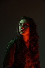 Portrait of beautiful young woman on dark background with neon lights