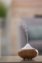 Photo of Aroma oil diffuser lamp on table against blurred background