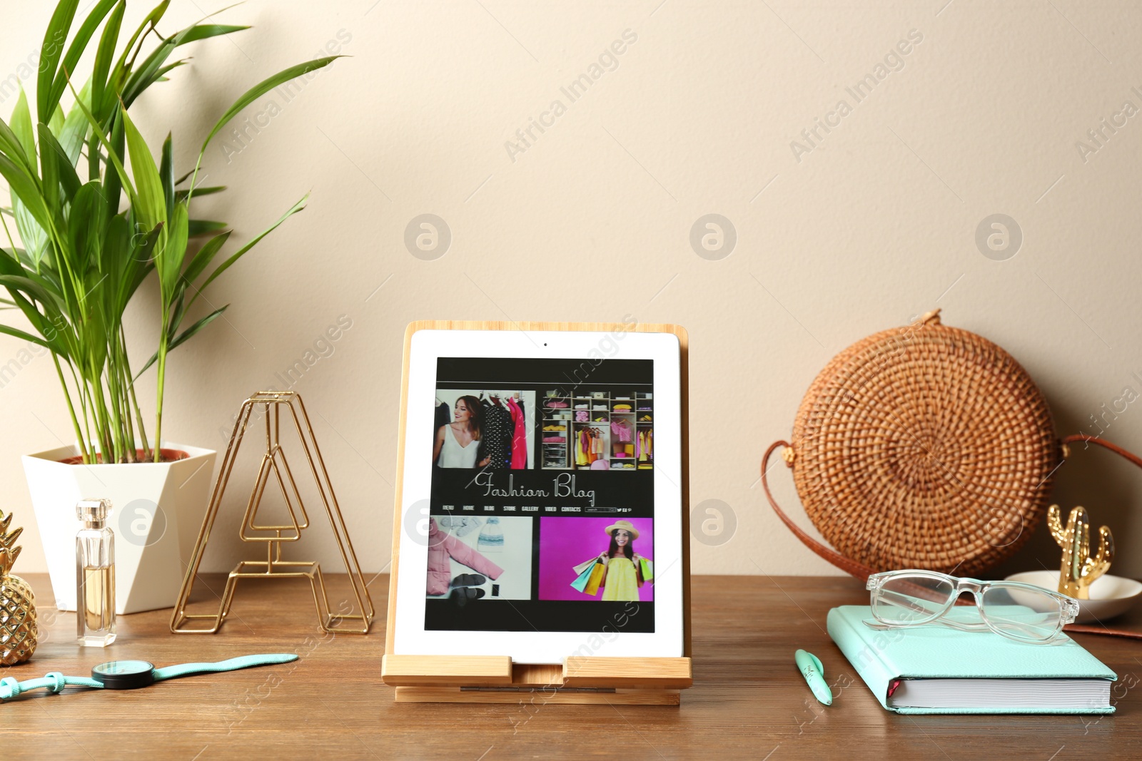 Photo of Stylish workplace with modern tablet on table near color wall. Fashion blogger