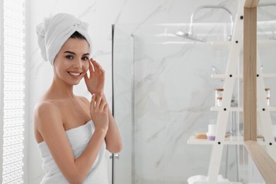 Photo of Happy young woman with towel on head in bathroom, space for text. Washing hair